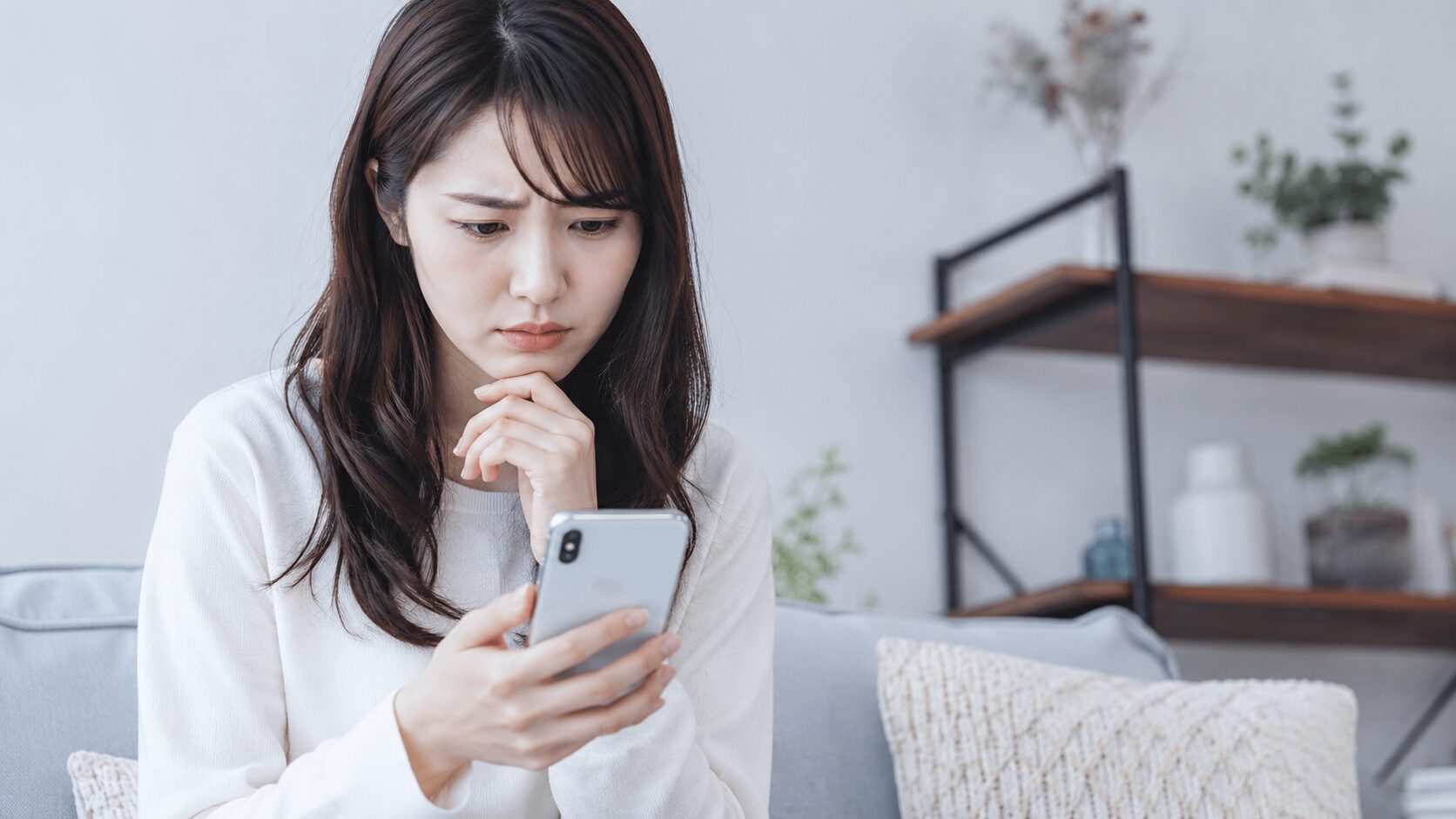 浮気の証拠が掴めずスマートフォンを見ながら悩む女性
